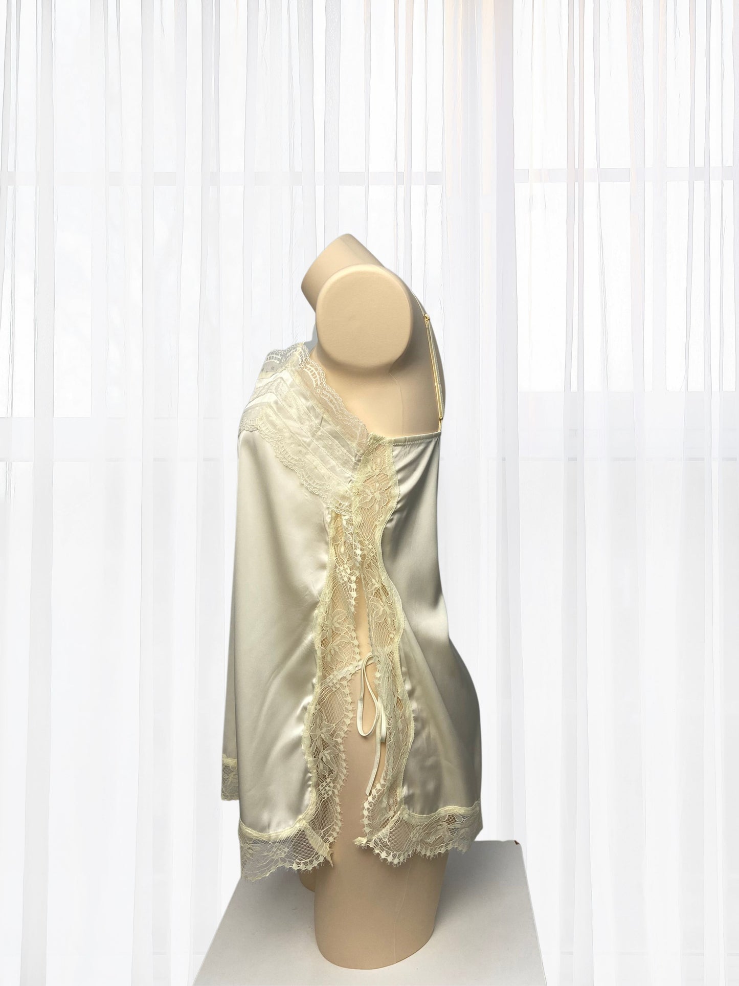 Mannequin wearing a cream-colored lace dress with gold accents against a white background
