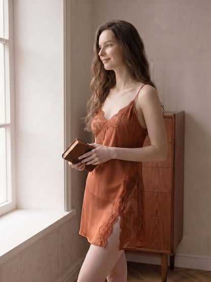 Woman in an orange slip dress holding a book by a window