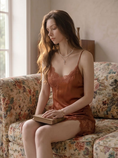 Woman in a rust-colored dress sitting on a floral couch holding a book.