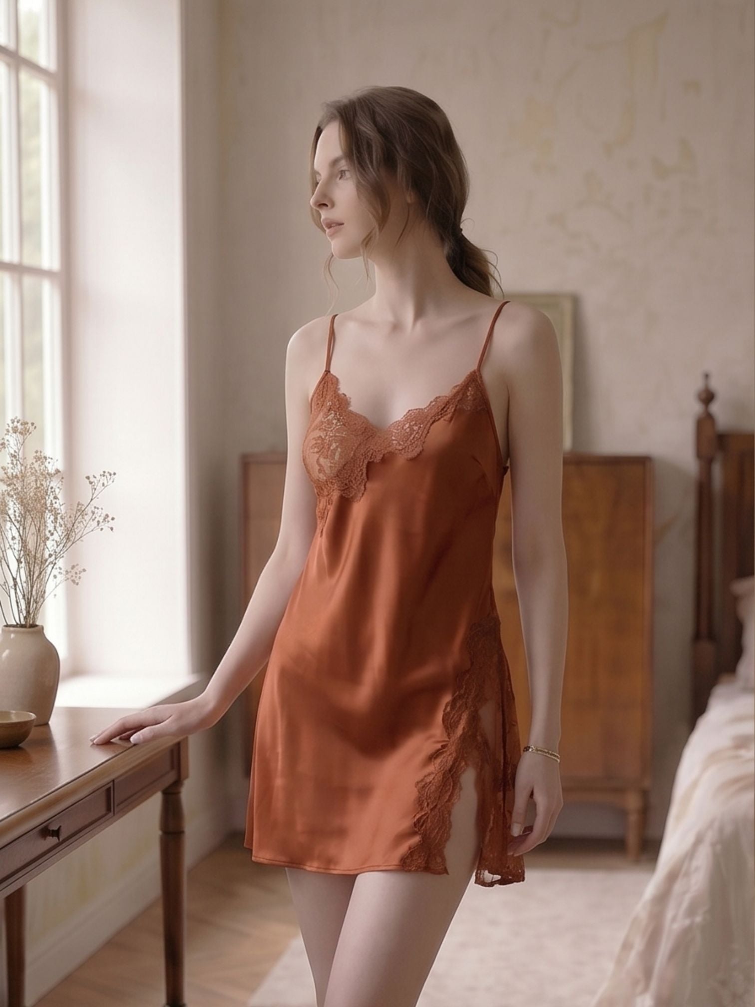 Woman wearing an orange satin slip in a softly lit bedroom.