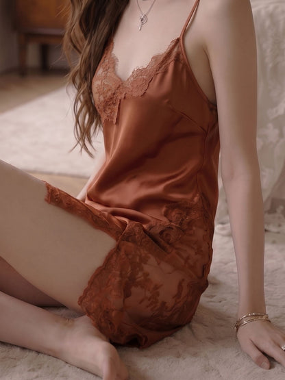 Woman wearing a rust-colored satin nightgown sitting on a bed.