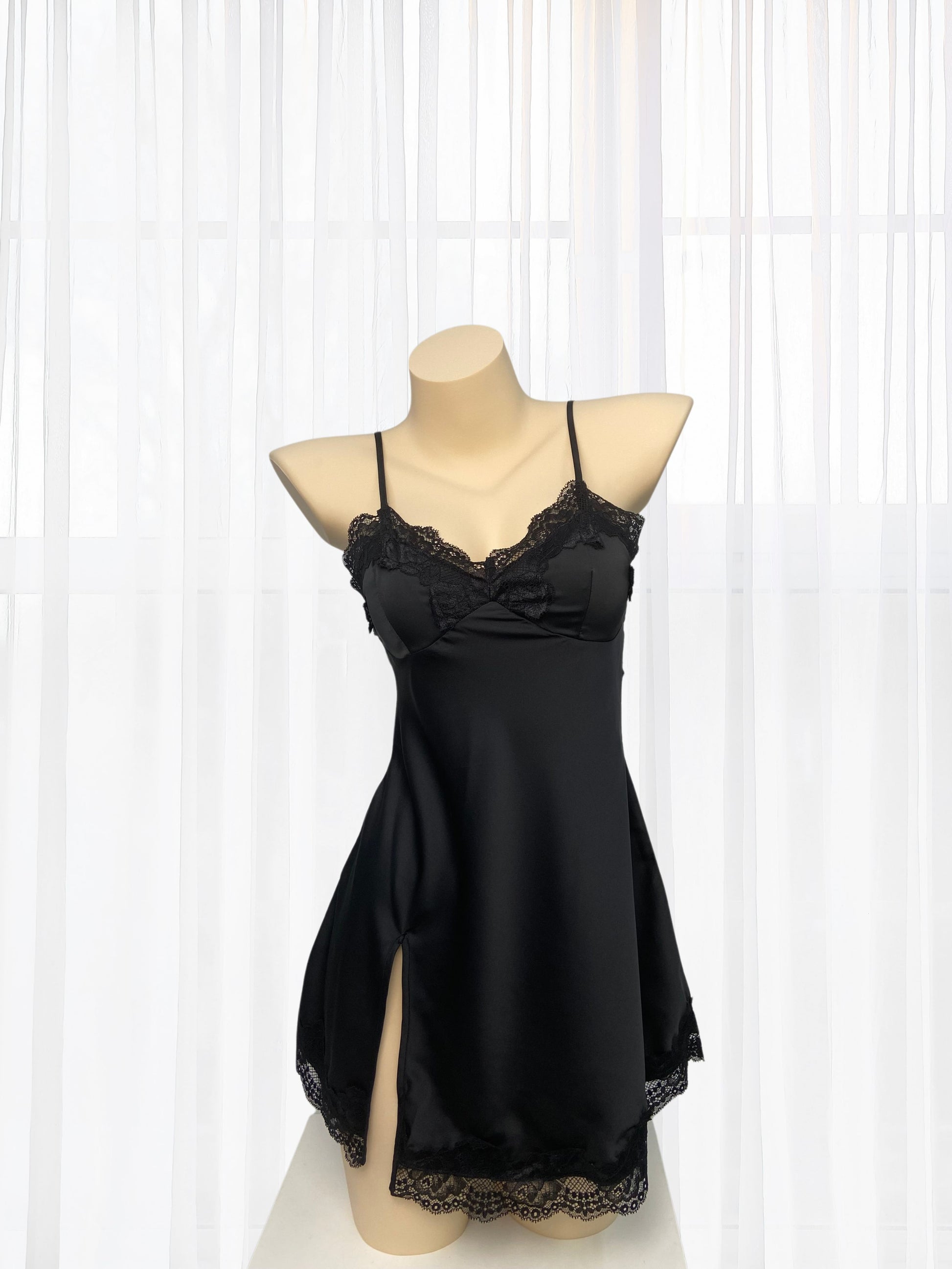 Black lace nightgown on a mannequin against a white curtain background